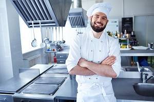 Male chef standing in the kitchen with hands folded