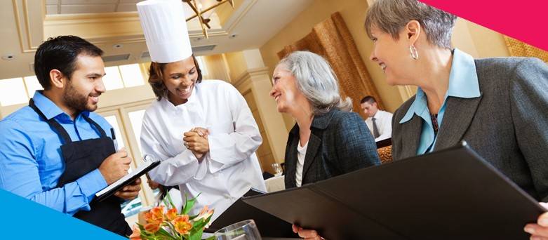 Head chef and waiter talking to 2 females as they order dinner