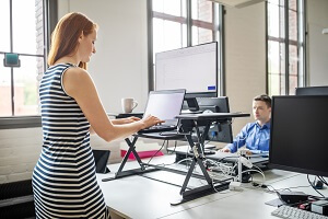 Picture of an office worker standing working on a raised desk