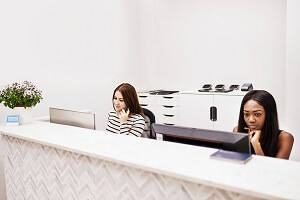 Two Receptionists working at a Reception Desk