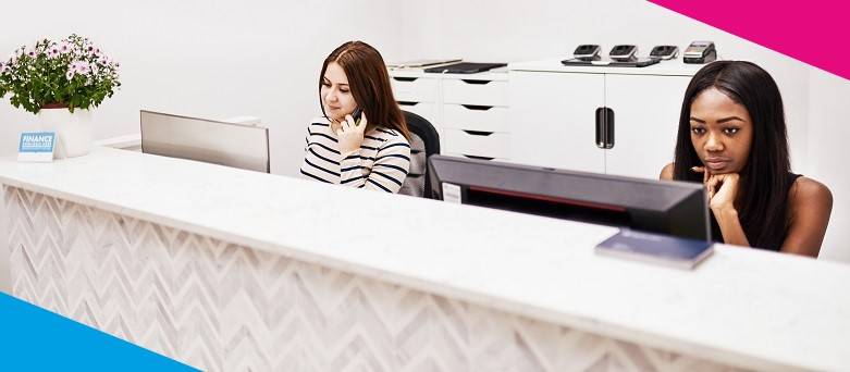 Two Receptionists working at a Reception Desk