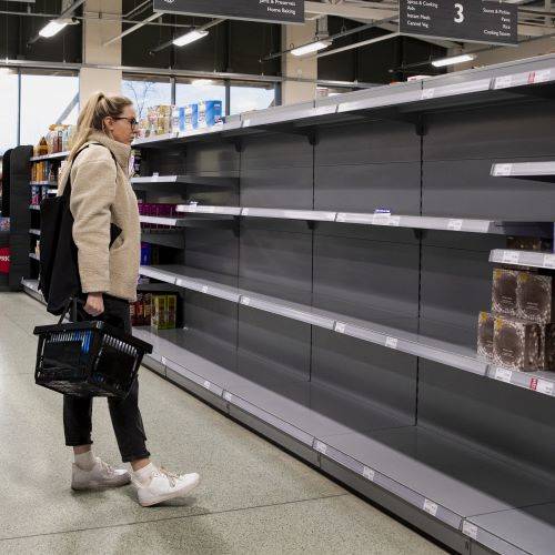 Woman in supermarket looking at empty shelves