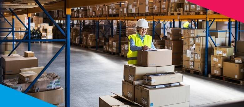 Being a Warehouse Operative  - Female Warehouse Operative leaning on a stack of boxes writing 